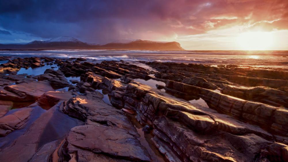 Serene Coastal Sunset Over Rocky Shoreline wallpaper
