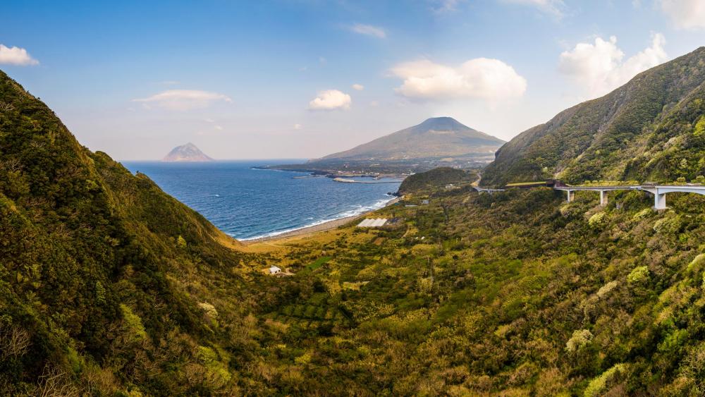 Serene Coastal Landscape with Lush Mountains wallpaper