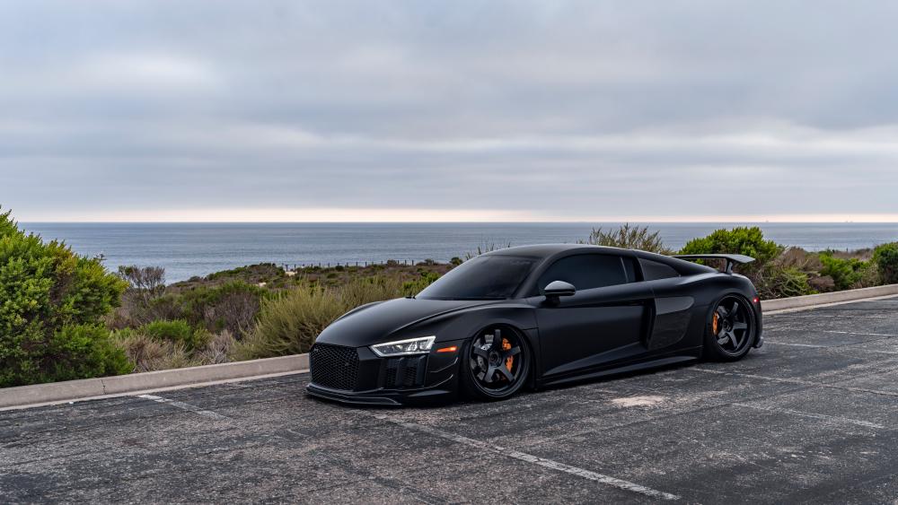 Sleek Black Sports Car Against Ocean Vista wallpaper