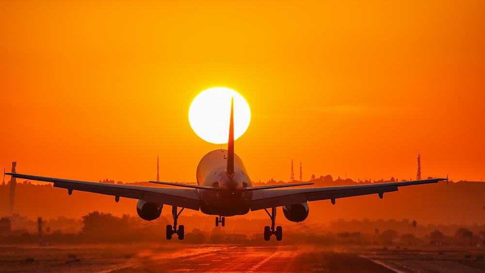 Airplane Silhouette Against Sunset Glow wallpaper