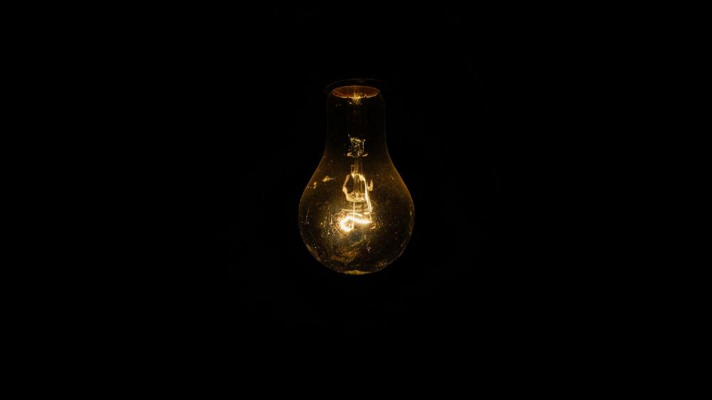 A light bulb glowing in the dark wallpaper