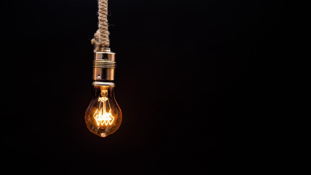 Illuminated Light Bulb Against Black wallpaper