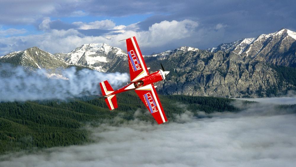 Thrilling Aerobatic Flight Over Majestic Peaks wallpaper