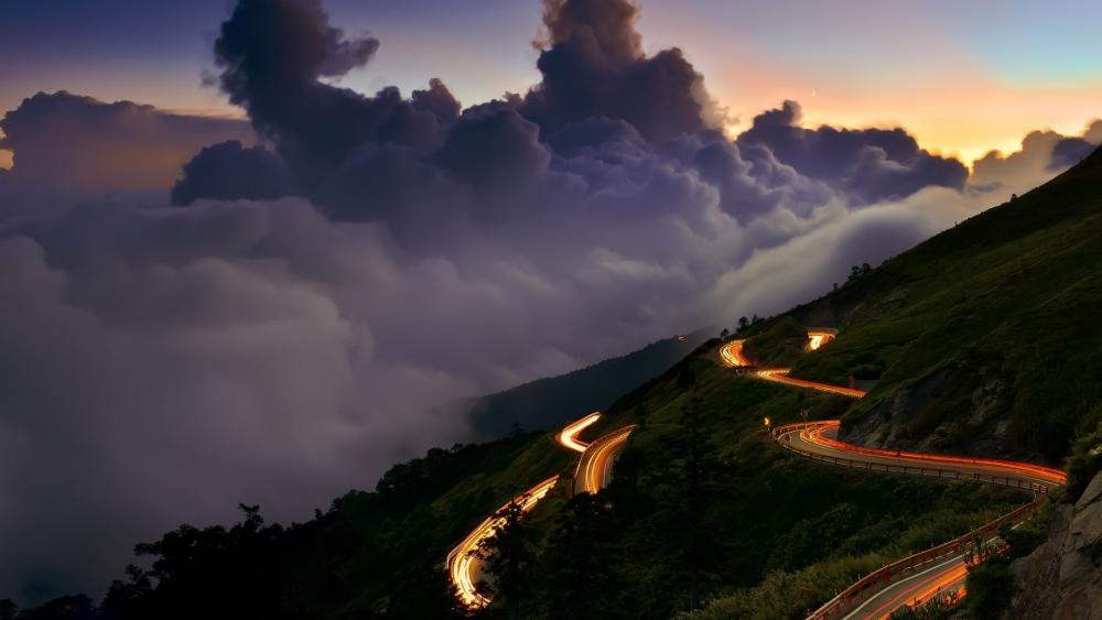 Winding Road Through Majestic Mountains at Dusk wallpaper