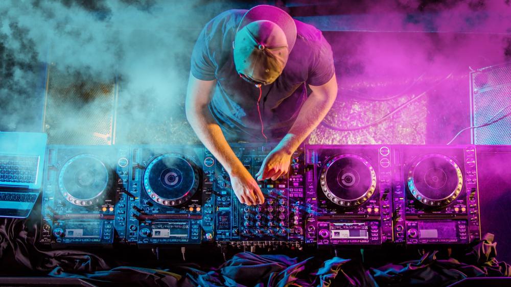 DJ in Action Amid Vibrant Lights and Smoke wallpaper