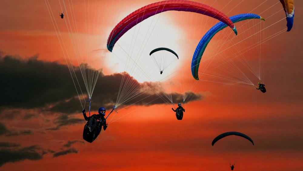 Paragliders Soar Against a Fiery Sunset Sky wallpaper