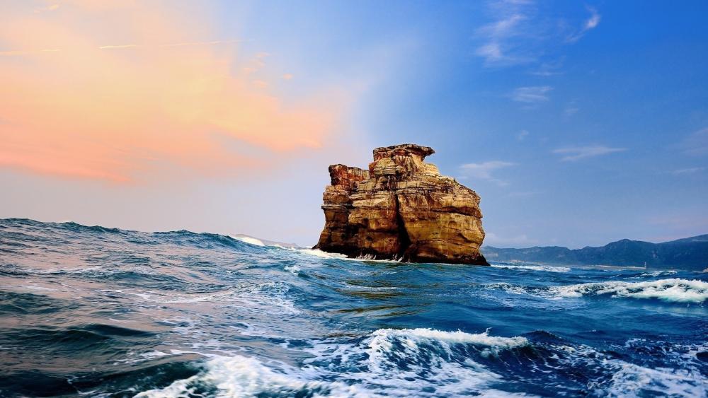 Majestic Rock Formation Amidst Ocean Waves wallpaper