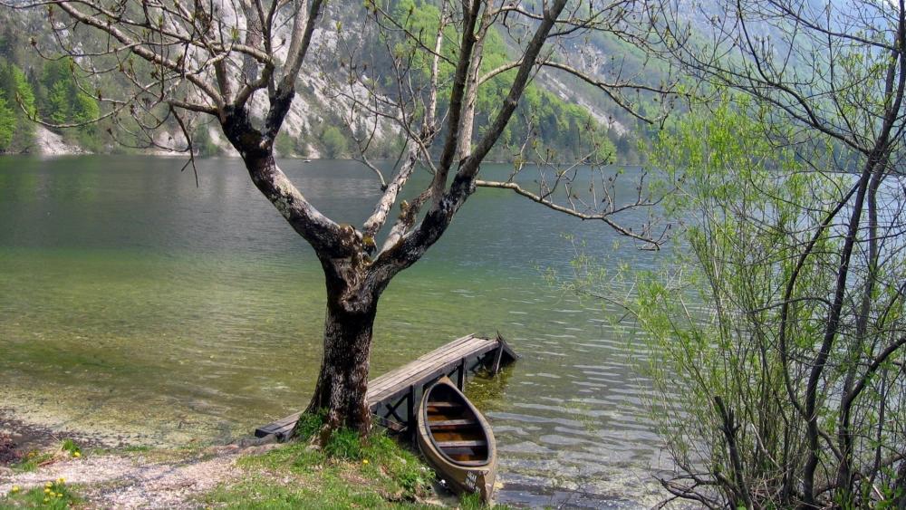 Tranquil Lake with Lonely Boat and Majestic Mountains wallpaper