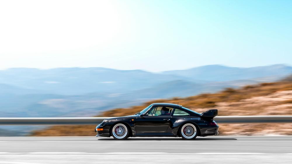 Sleek Porsche Driving Through Scenic Landscape wallpaper