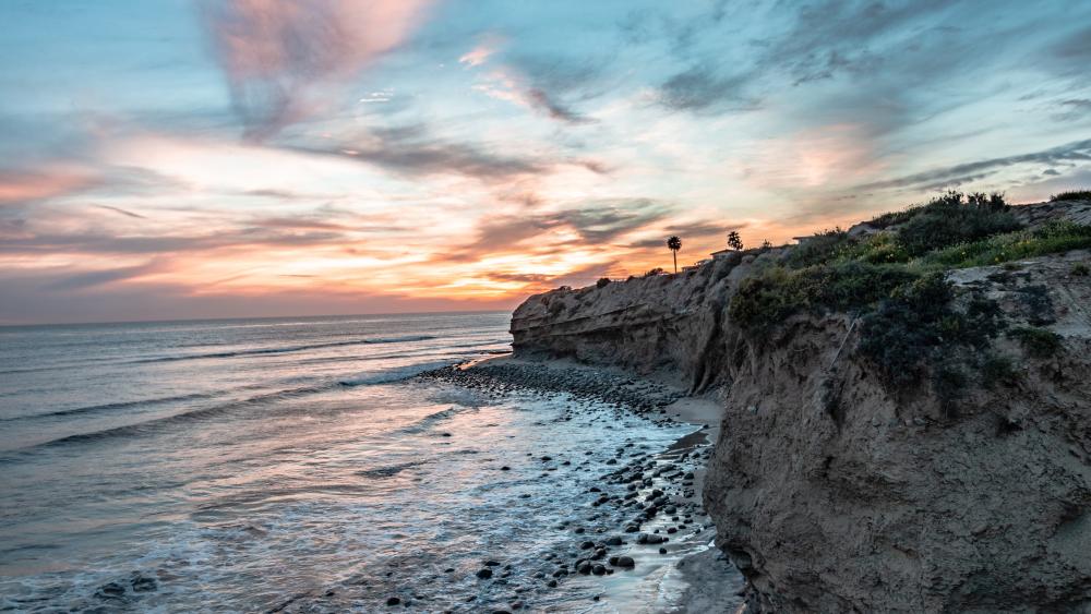 Serene Coastal Sunset Over Rocky Shores wallpaper