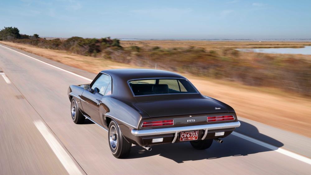 Classic Chevrolet Camaro Driving on Open Road wallpaper