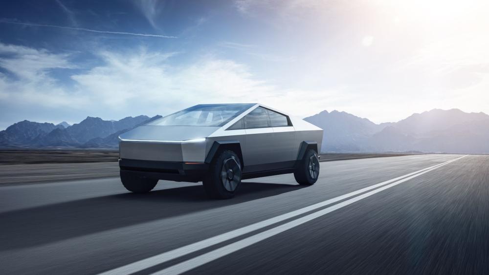 Tesla Cybertruck and remote desert highway with mountain ranges in the distance under a bright sky. wallpaper