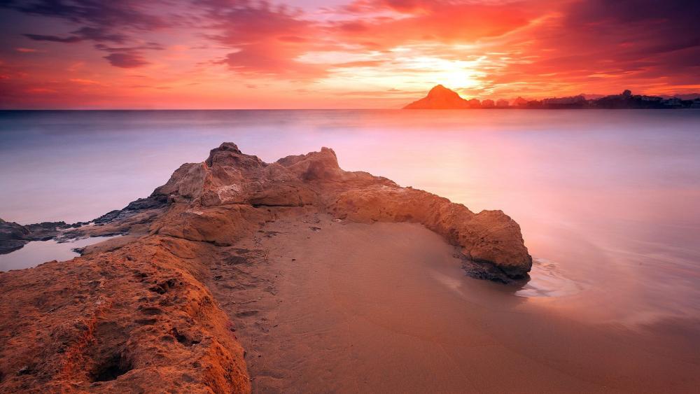 Crimson Sundown Over a Quiet Rocky Coastline Horizon wallpaper