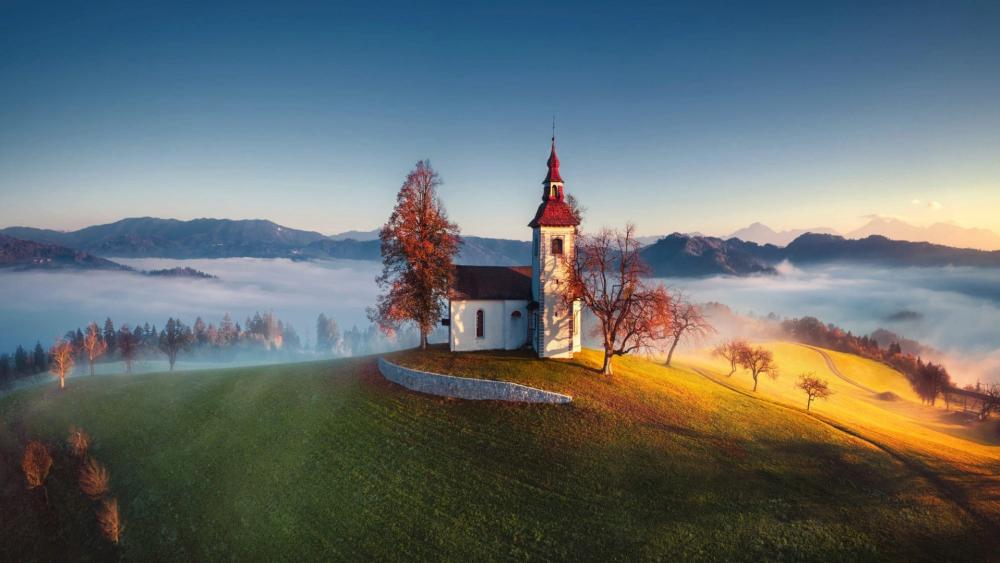 Misty Sunrise Over Saint Thomas Church in the Slovenian Alps wallpaper