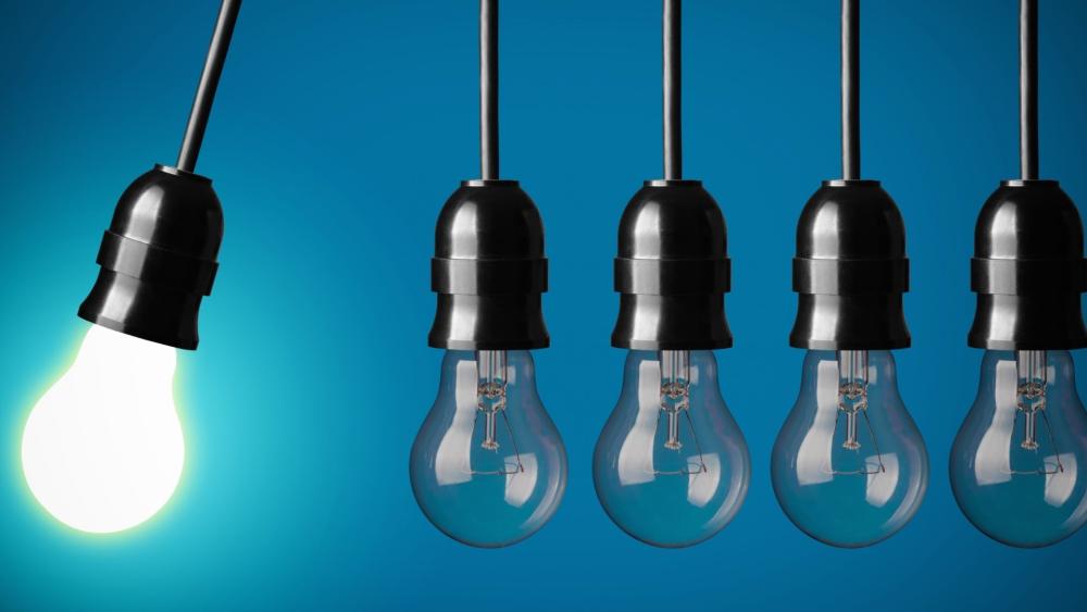 Single Bright Idea Among Silent Hanging Bulbs wallpaper