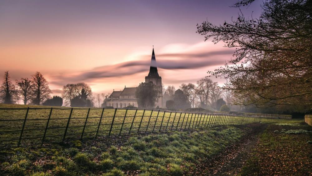 Misty Sunrise Over a Countryside Church Beyond Quiet Fields wallpaper