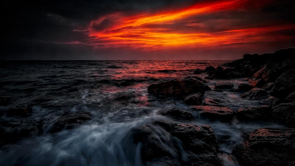Crimson Twilight Over a Stormy Sea Horizon in Burning Sunset Glow wallpaper