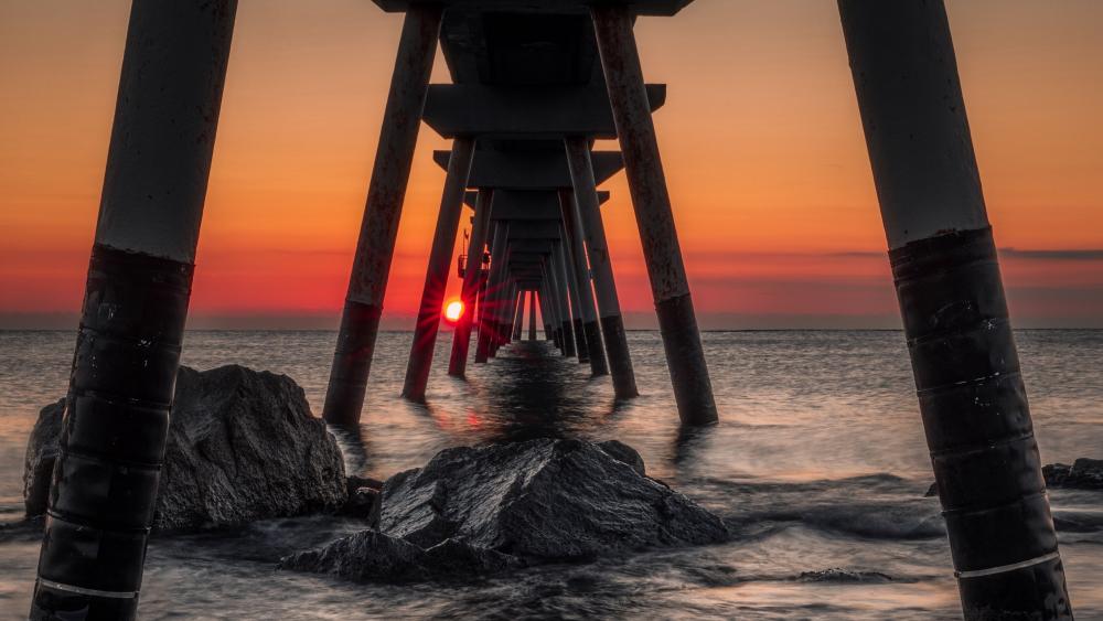 Sunset Afterglow Beneath the Pier Over Calm Ocean Rocks wallpaper