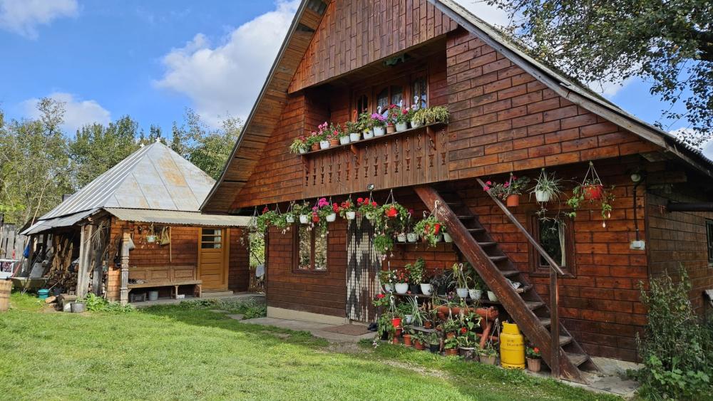 Flower Adorned Wooden Cottage Home Under Bright Blue Skies wallpaper