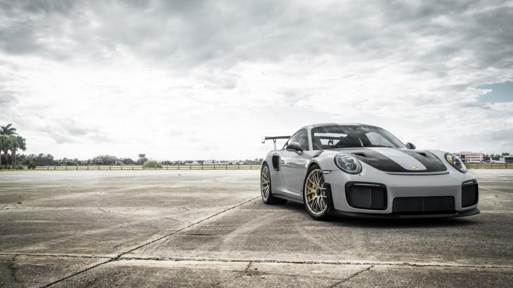Porsche 911 GT2 Poised on Open Tarmac Under Brooding Skies wallpaper