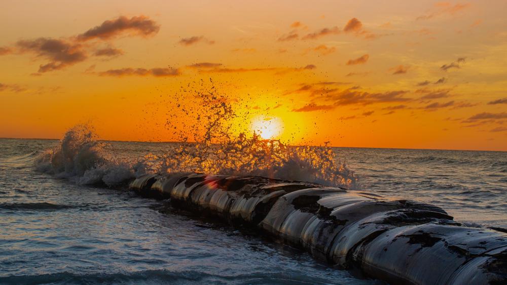 Golden Sunset Waves Crashing Over a Sea Breakwater in 4K wallpaper
