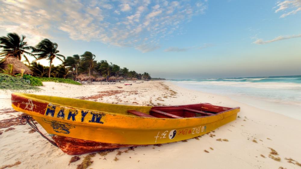Windy Tropical Shore with a Yellow Boat Resting on White Sand wallpaper