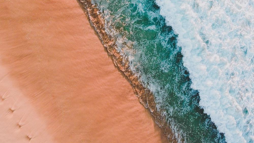 Aerial Tide Meeting Turquoise Sea Along Sunlit Sandy Coast wallpaper
