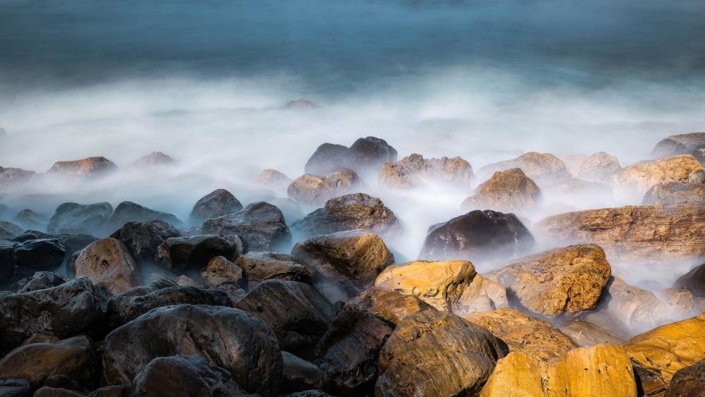 Misty Coastal Boulders in Soft Morning Surf wallpaper