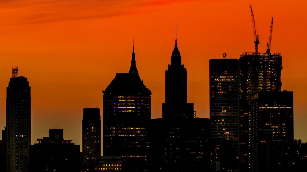 Silhouetted Skyscrapers and Cranes Against a Fiery Dusk Skyline wallpaper