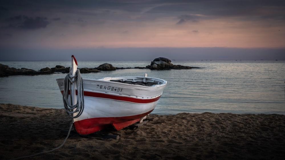 Quiet Fishing Boat Resting on a Sandy Shore at Dusk wallpaper