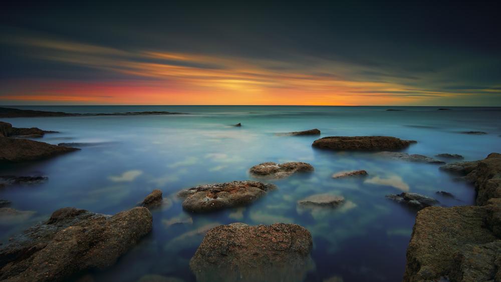 Serene Dusk Coastline with Rocky Shores and Silky Sea wallpaper