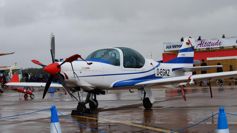Grob G 120TP Trainer Aircraft on Rainy Airfield in 4K wallpaper