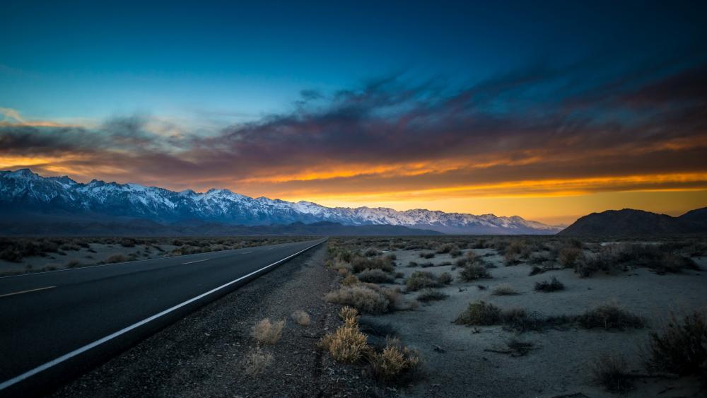 Endless Desert Highway at Dusk Beneath Snowy Mountains wallpaper