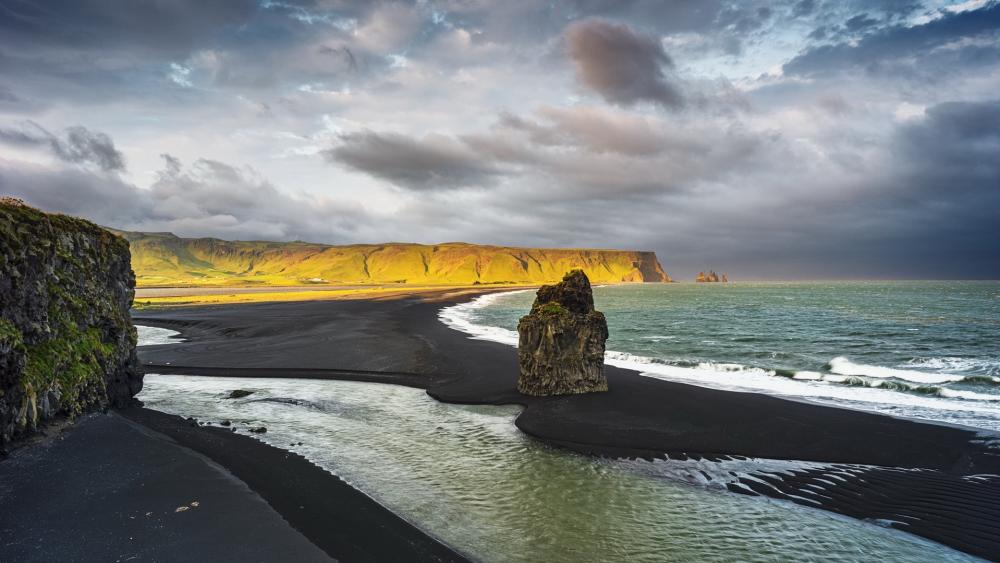Stormlit Black Sand Coastline and Sea Stack in Vík í Mýrdal Iceland wallpaper
