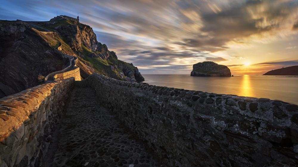 Sunset Pathway Along Rugged Coastal Cliffs and Calm Sea wallpaper