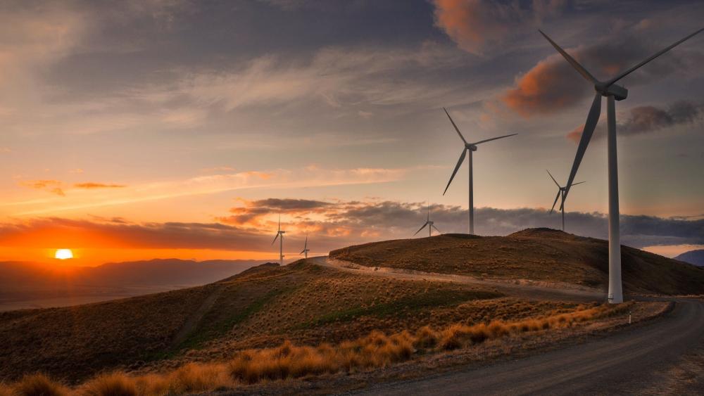 Sunset Over Rolling Hills and Wind Turbines on the Horizon wallpaper