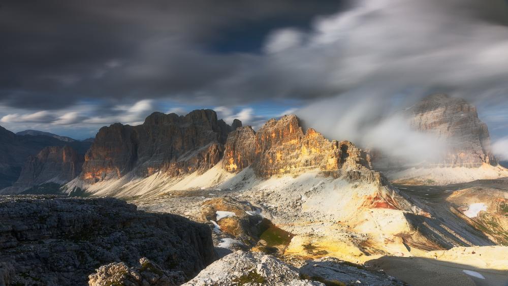 Sunlit Dolomites Beneath Sweeping Alpine Clouds wallpaper