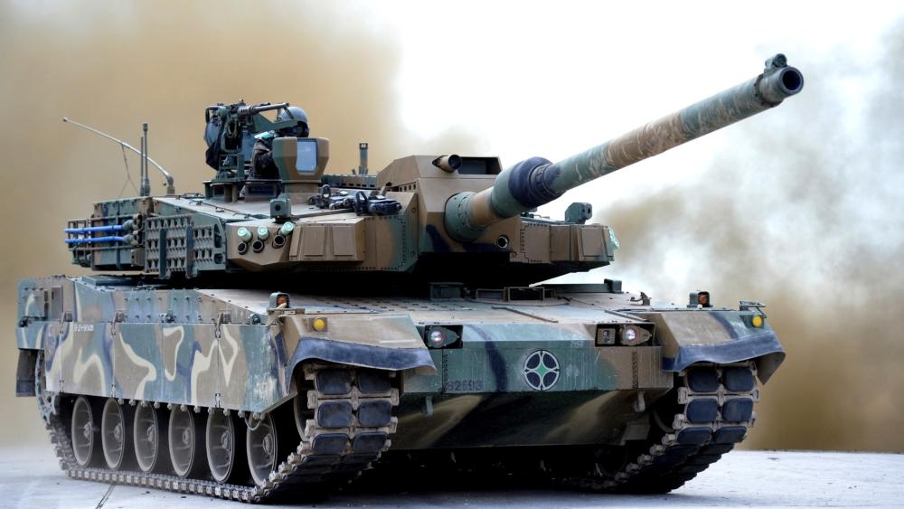 Camouflaged Battle Tank Charging Forward wallpaper