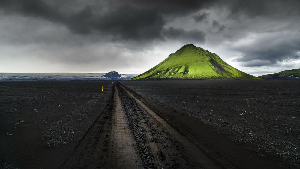 Moss Green Volcano Under Stormy Icelandic Skies wallpaper
