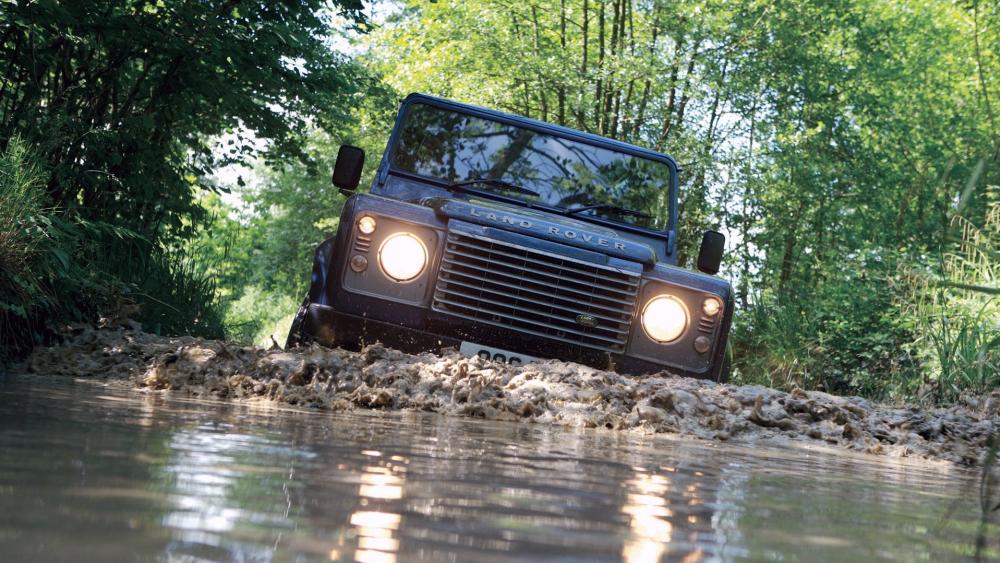 Rugged Defender Conquers Muddy Forest Trail wallpaper