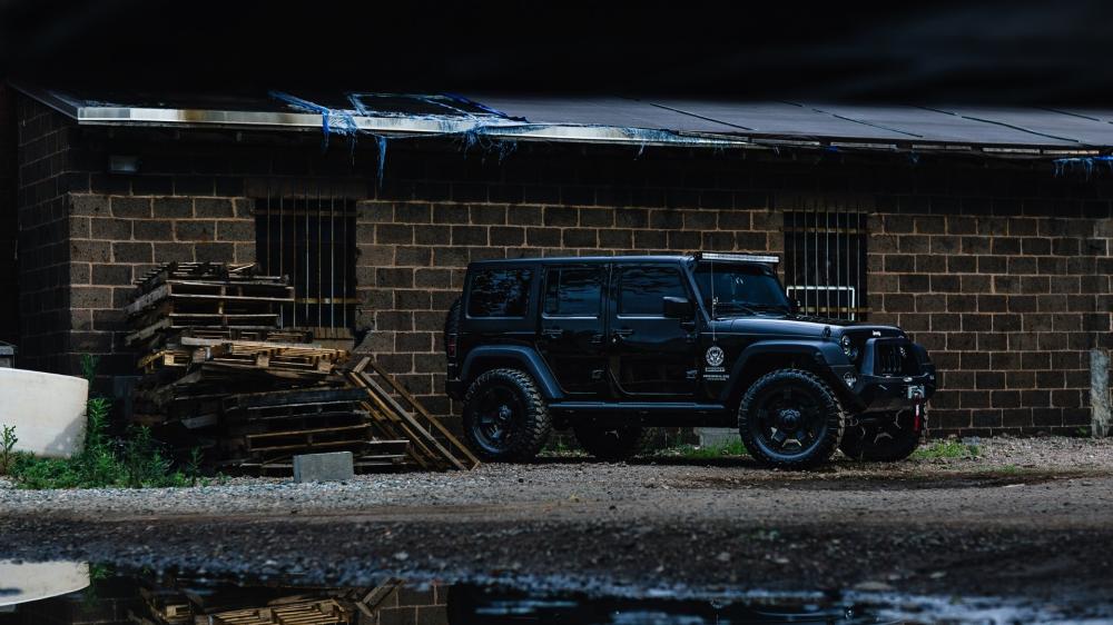 Rugged Black Jeep Wrangler in Industrial Setting wallpaper