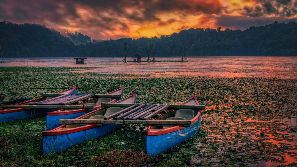 Serene Sunset Over Calm Lake with Canoes wallpaper
