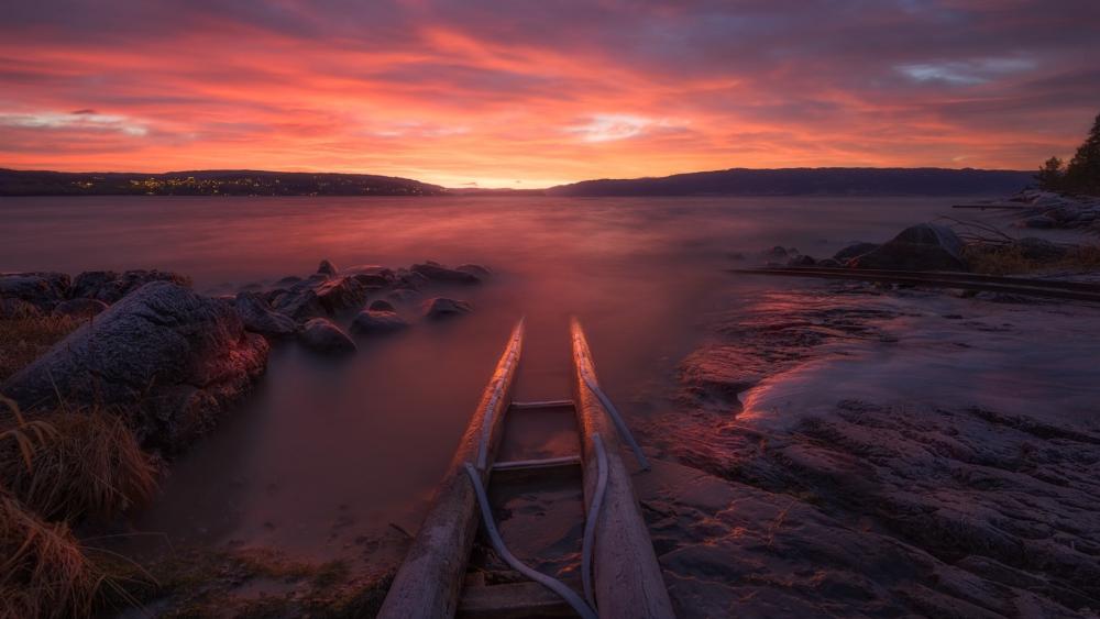 Pink Sunset Over Calm Lake Shoreline wallpaper