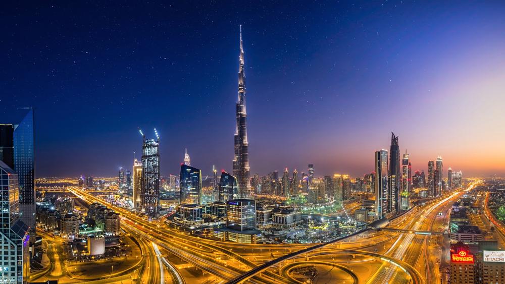 Dubai Skyline Glowing Above Busy Expressways wallpaper