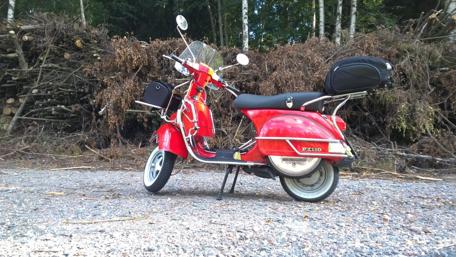 Classic Red Vespa Scooter in Nature Scene wallpaper