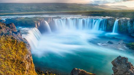 Majestic Waterfall Amidst Verdant Highlands wallpaper