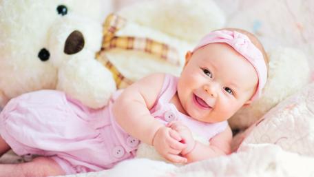 Joyful Baby Smiling with Teddy Bear in Pastel Room wallpaper