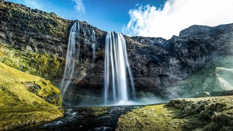 Majestic Waterfall Surrounded by Lush Landscape wallpaper