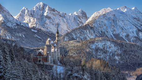 Majestic Bavarian Castle Amid Snowy Peaks wallpaper