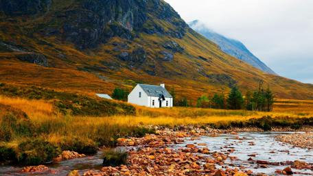Serene Cottage Amidst Majestic Mountains and Tranquil Creek wallpaper